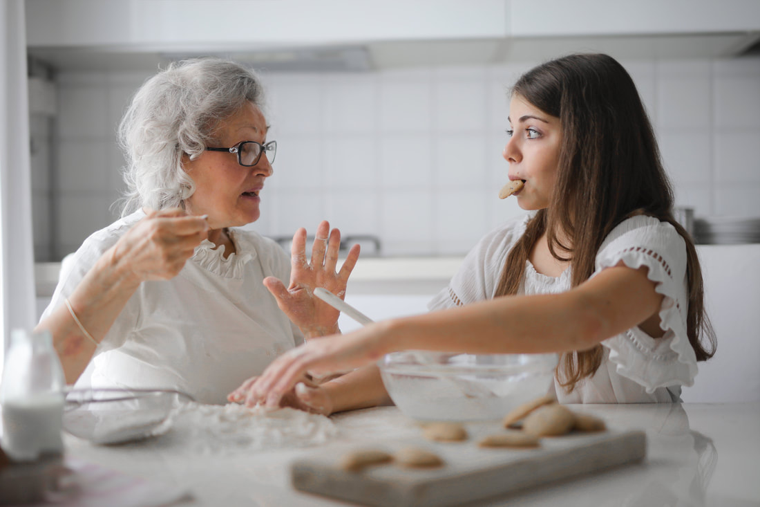 Young girl helping old woman bake some cookies