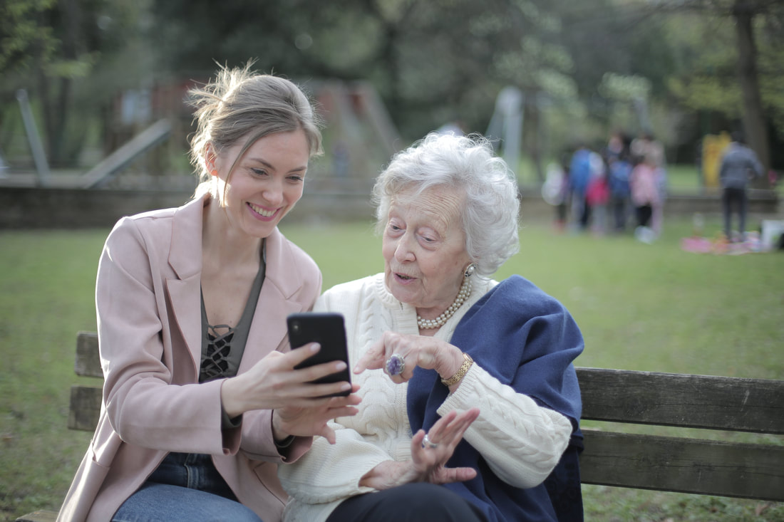 Young woman assisting old woman use her phone