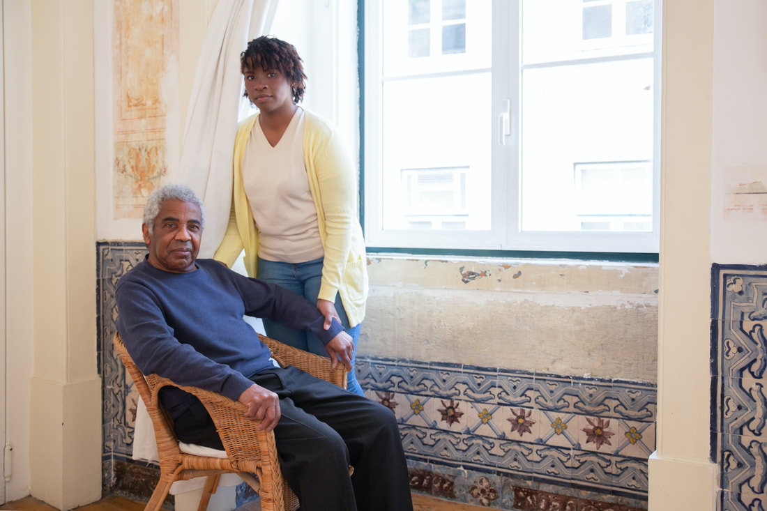 Caregiver assisting elderly man sitting